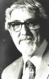 Portrait of Leonard Salzedo in his 60s, with glasses, moutstache and beard and wearing a suit, shirt and tie