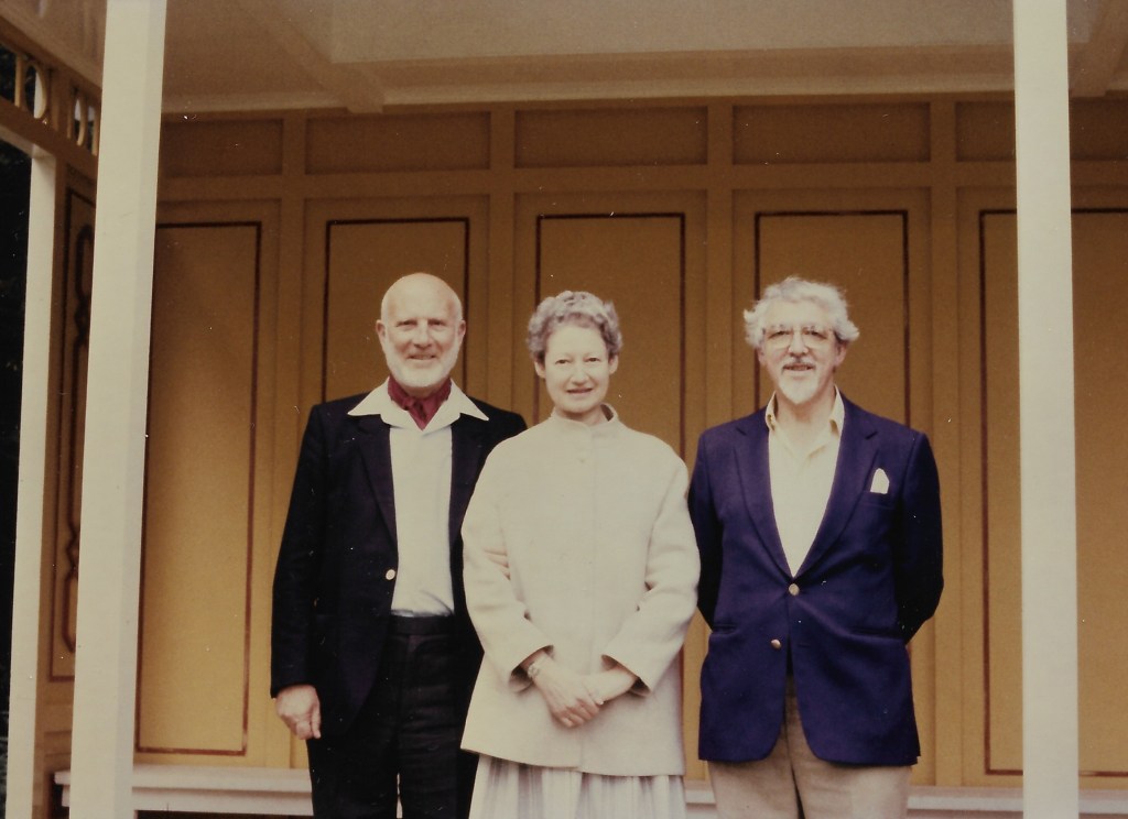 John Cromer Braun in his 50s, Pat Braun, Leonard Salzedo, in their 40s, standing on a veranda looking at the camera