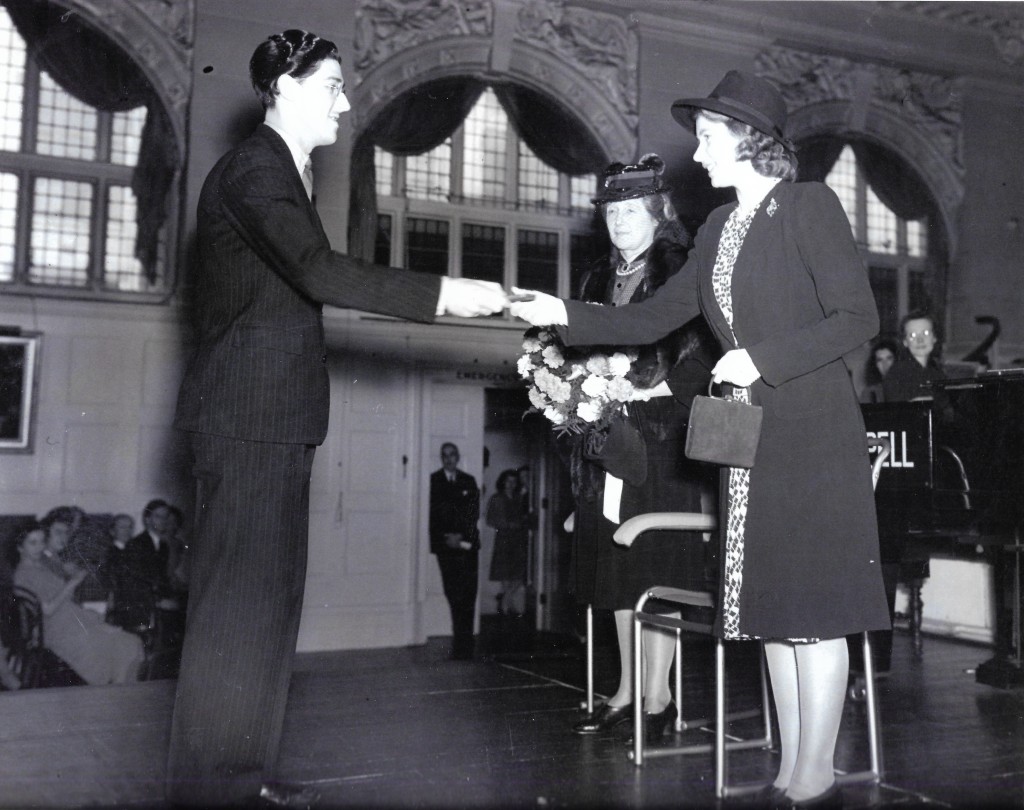 Young Leonard Salzedo standing, young Princess Elizabeth standing and handing him a medal