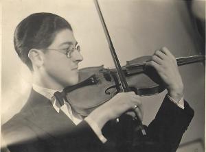 Black and white photo of young man, black hair, glasses, pictured from side, playing the violin