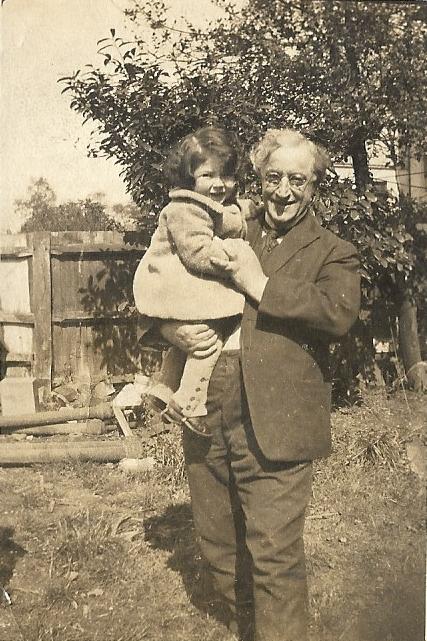 Father holding young son in back garden, both smiling