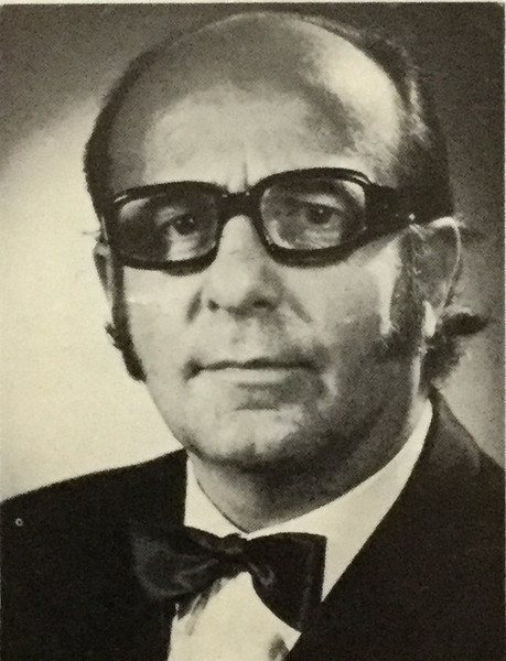 Black and White photo of man in his 50s, balding with glasses and wearing a bow tie. headshot.
