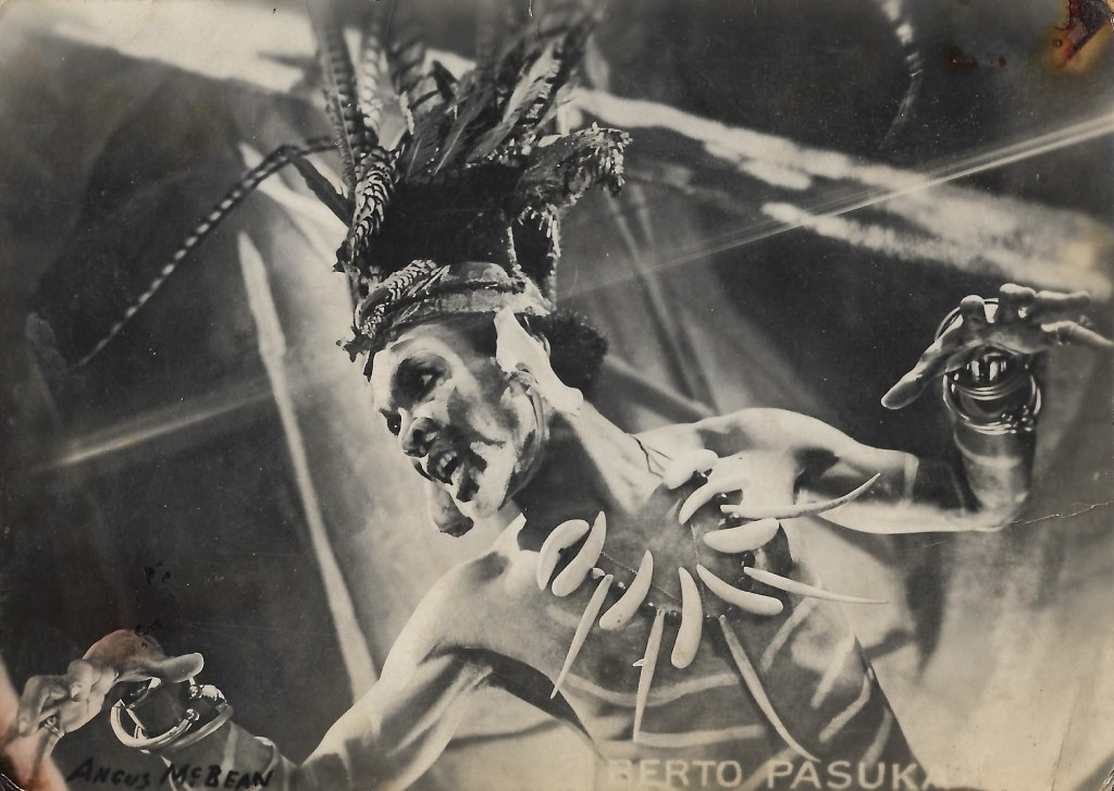 Black and white photo of man dressed as witch doctor and shaman with headdress and bone necklace