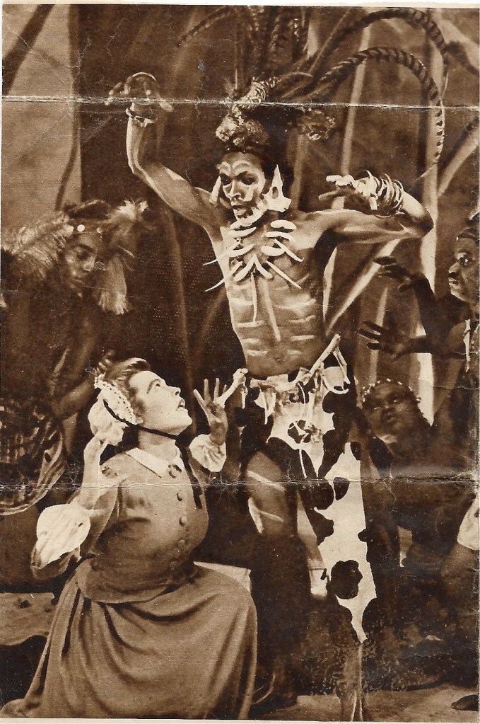 Black and white photo, man witch doctor standing over crouching woman, nurse